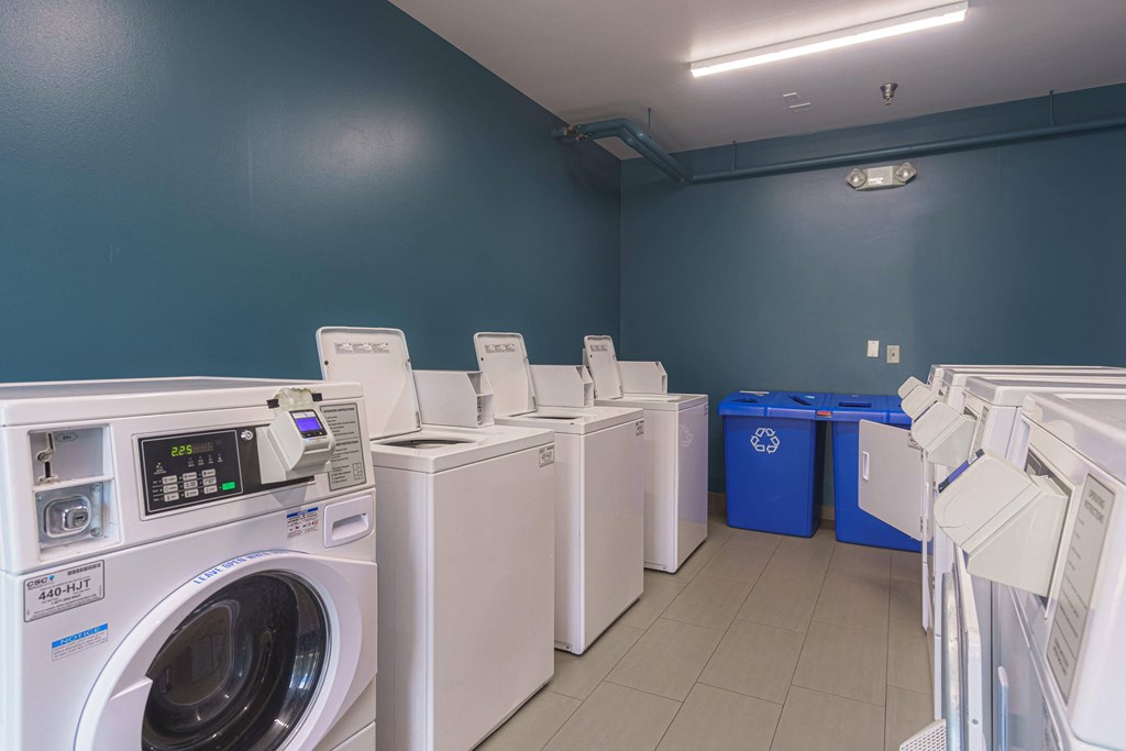 a row of washers and dryers in a laundry room with blue walls